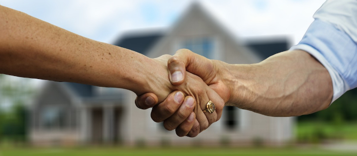 Image d'illustration représentant une poignée de main entre un homme et une femme devant une maison