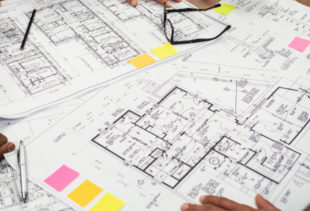 Image d'illustration représentant une table vue de haut où des plans d'appartements et de maisons sont entreposés