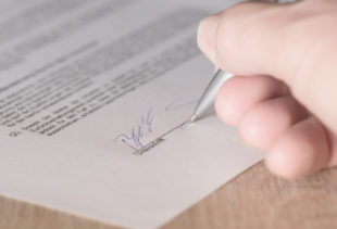 Image d'illustration représentant un contrat en train d'être signé par un homme